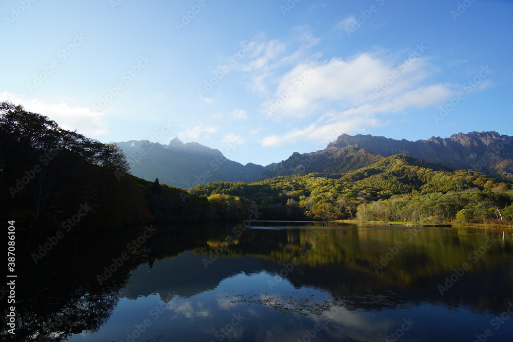 A pond that reflects trees and mountains like a mirror. At dusk. Beautiful scenery of Japan.