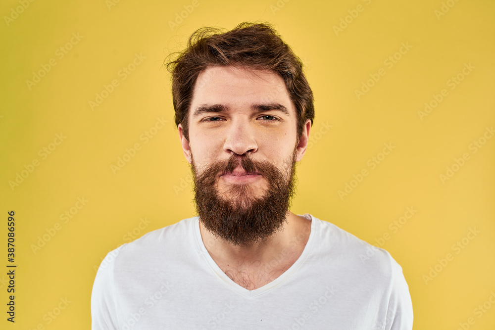 A man in a white t-shirt gestures with his hands lifestyle cropped view yellow background more fun A man in a white t-shirt gestures with his hands lifestyle cropped view yellow background more fun