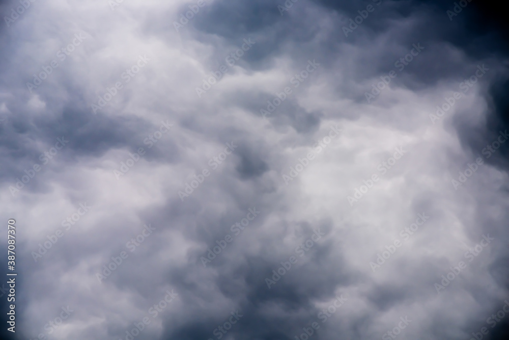 Thick gloomy white clouds on dark blue sky background
