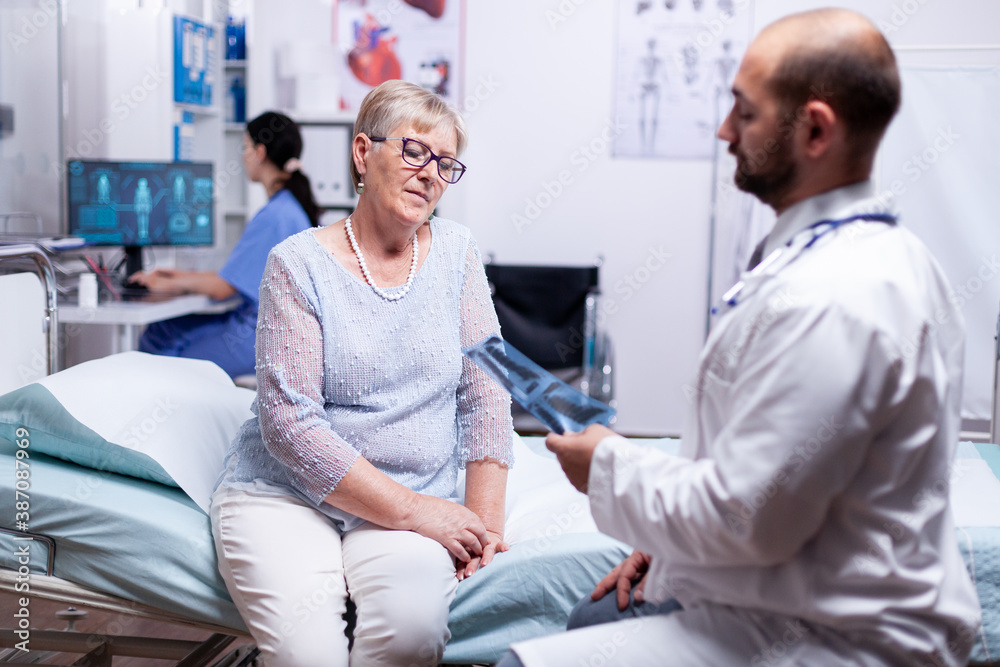 Obraz premium Doctor looking at patient x-ray while discussing diagnosis in hospital examination room. Healthcare medical medicinal system, disease prevention treatment, illness diagnosis