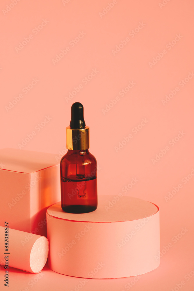 glass bottle with cosmetic product with pipette on a pink pedestal on a pink background