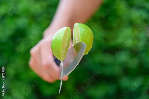 The man use knife split the fresh green lemon in midair