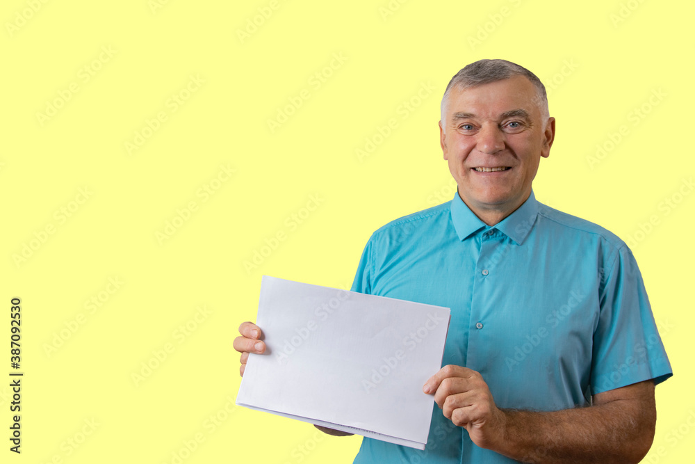Cheerful man shows a blank sheet of paper. Isolated on yellow Cheerful man shows a blank sheet of paper. Isolated on yellow