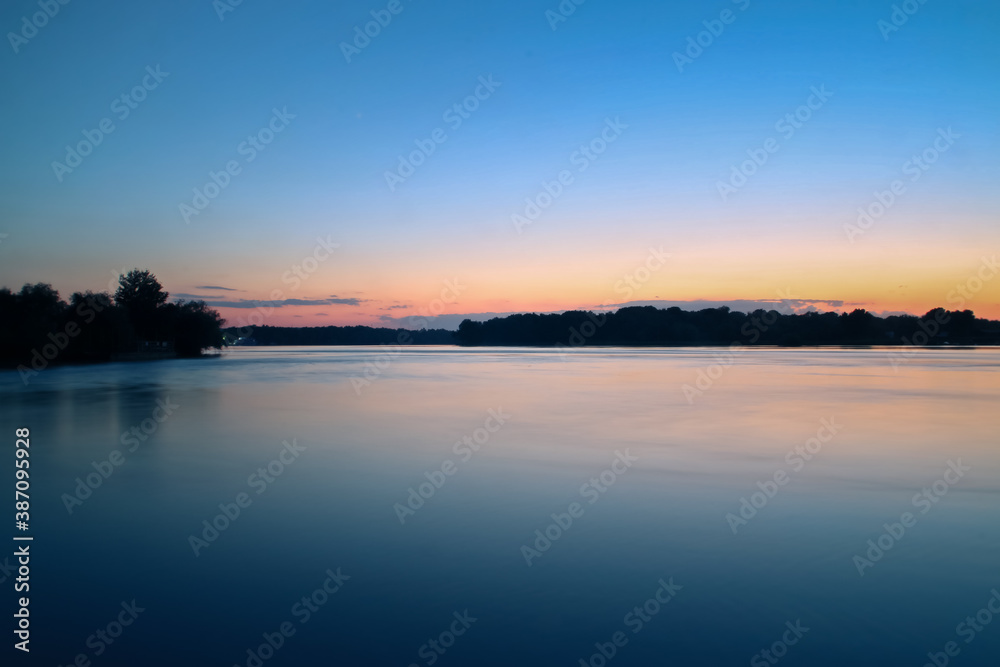 Puesta de sol a orillas del río Danubio. Reflejo del cielo colorido en la superficie del agua del delta del Danubio en la localidad de Nufaru, Rumanía.