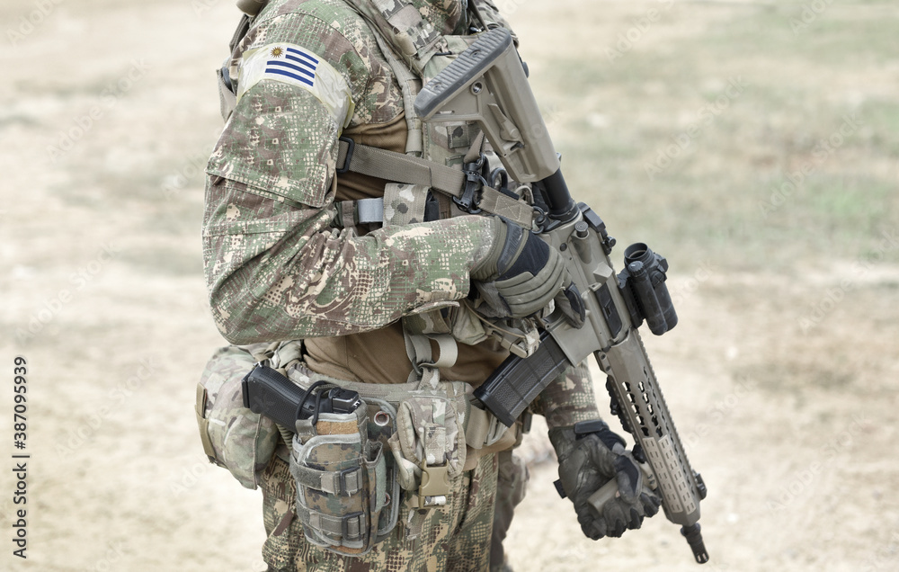 Fototapeta premium Soldier with assault rifle and flag of Uruguay on military uniform. Collage.
