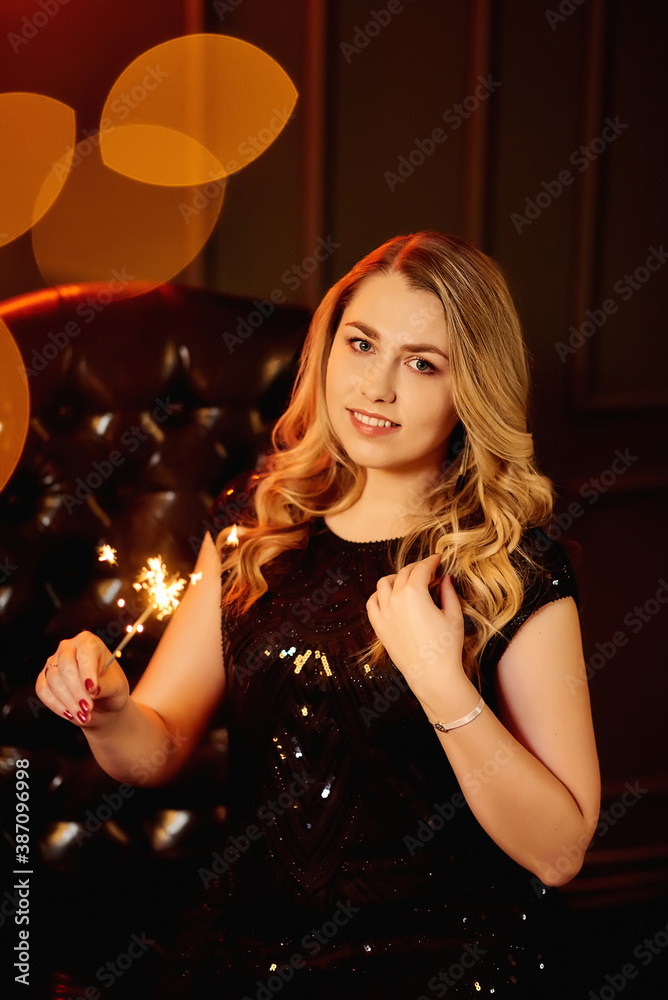 Smiley beautiful blonde girl in a black dress holds a Bengali fire