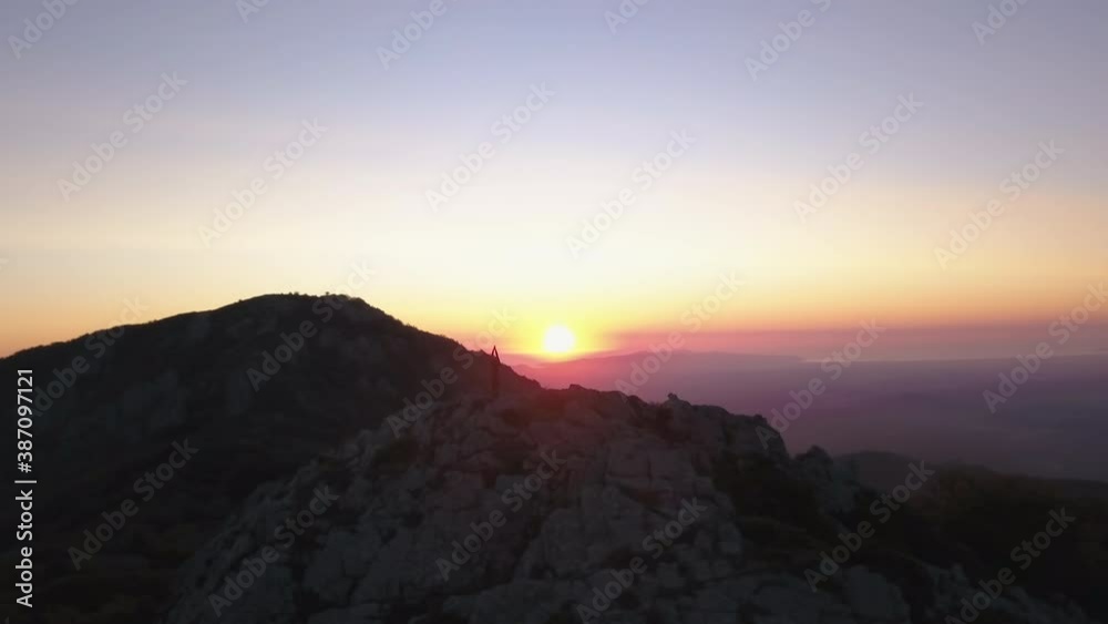 Parallax drone shot of a woman doing yoga on top of a mountain. In the background the Mediterranean and the sunrise. 4K Pro Res Parallax drone shot of a woman doing yoga on top of a mountain. In the background the Mediterranean and the sunrise. 4K Pro Res