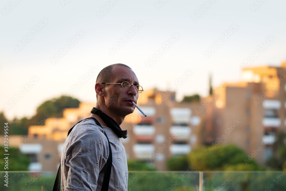 Young man standing on the balcony, smoking a break from work. Home office. Man smoking a cigarette Young man standing on the balcony, smoking a break from work. Home office. Man smoking a cigarette