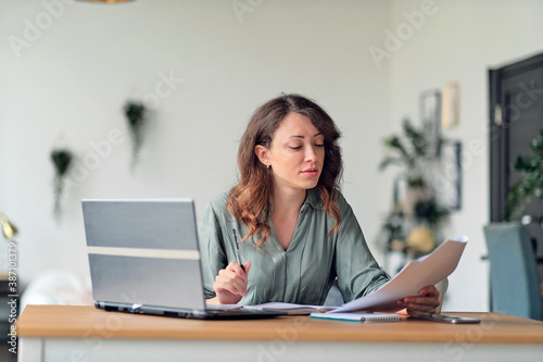 Young woman working from home office. Freelancer using laptop and the Internet. Workplace in living room.