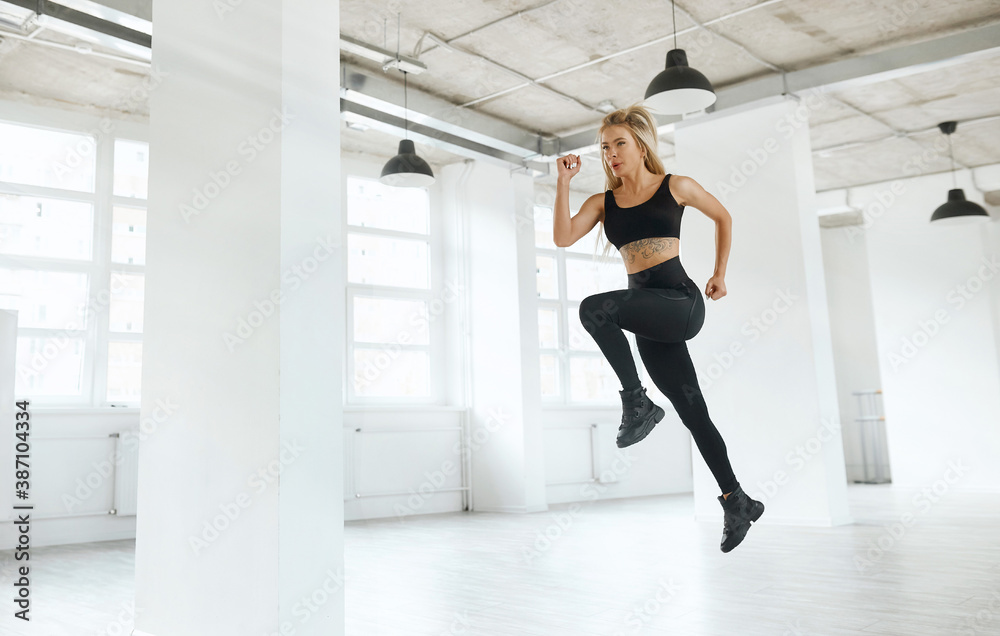 young blonde in a tracksuit runs in a white room. sportswoman doing sports in the morning young blonde in a tracksuit runs in a white room. sportswoman doing sports in the morning