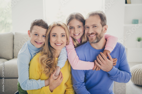Photo of idyllic positive family mom dad carry piggyback two small kids in house indoors