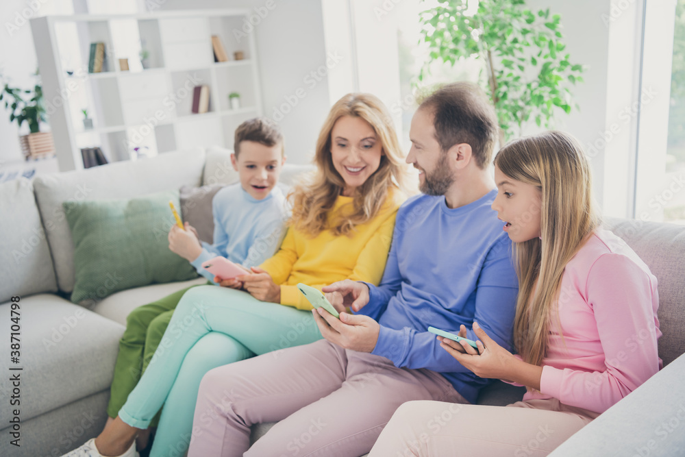 Photo of shocked people family sit sofa daddy show social media news cellphone mommy and two small kids in house indoors