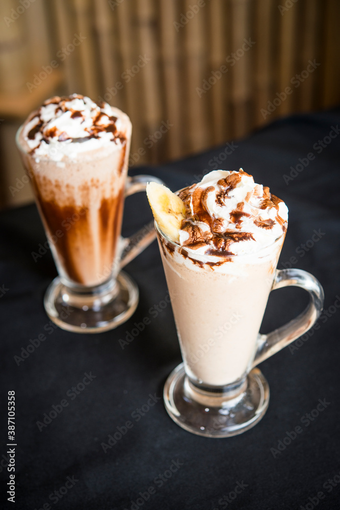 Two Iced coffee milkshake on a wood table with a wood background Two Iced coffee milkshake on a wood table with a wood background