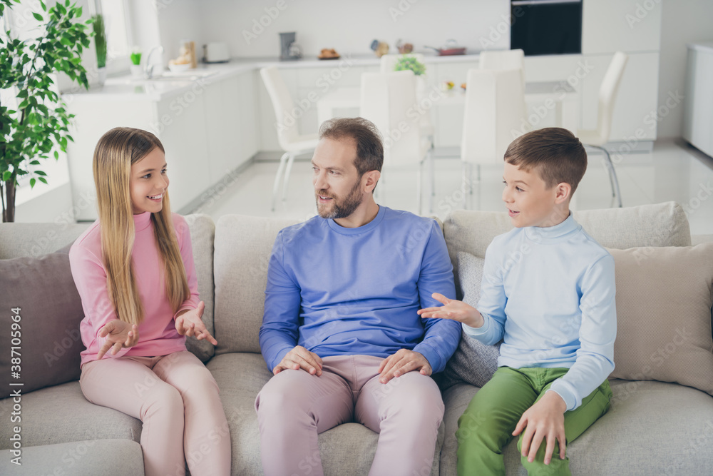 Obraz premium Photo of positive father and two children boy girl talking on weekend sit divan in house living room