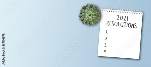 2021 new years resolutions and goals concept with notepad on wide blue table background