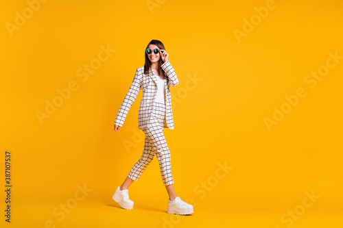 Full length body size side profile photo of girl wearing black sunglass walking smiling isolated on bright color background with empty space