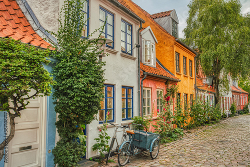 Photo A traditional Scandinavian Cargo bicycle (Christiania Bike) parked at a house entrance in a cozy downtown street by a colorful facade