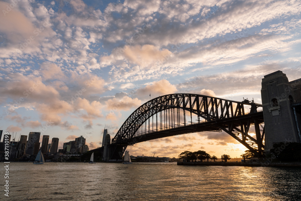 Sydney Harbour Bridget at sunset with golden light in the background and clouds in the sky Sydney Harbour Bridget at sunset with golden light in the background and clouds in the sky