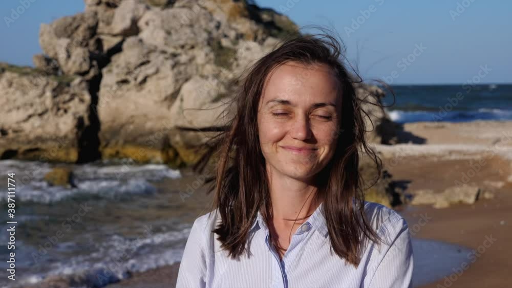 Portrait of a young happy woman at the beach. Female with windswept hair enjoying summer vacation at beach. Portrait of a young happy woman at the beach. Female with windswept hair enjoying summer vacation at beach.