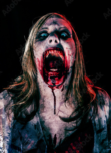 Studio portrait of a female vampire of zombie looking at camera. Black background.