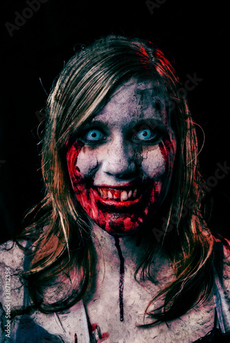 Studio portrait of a female vampire of zombie looking at camera. Black background. photo