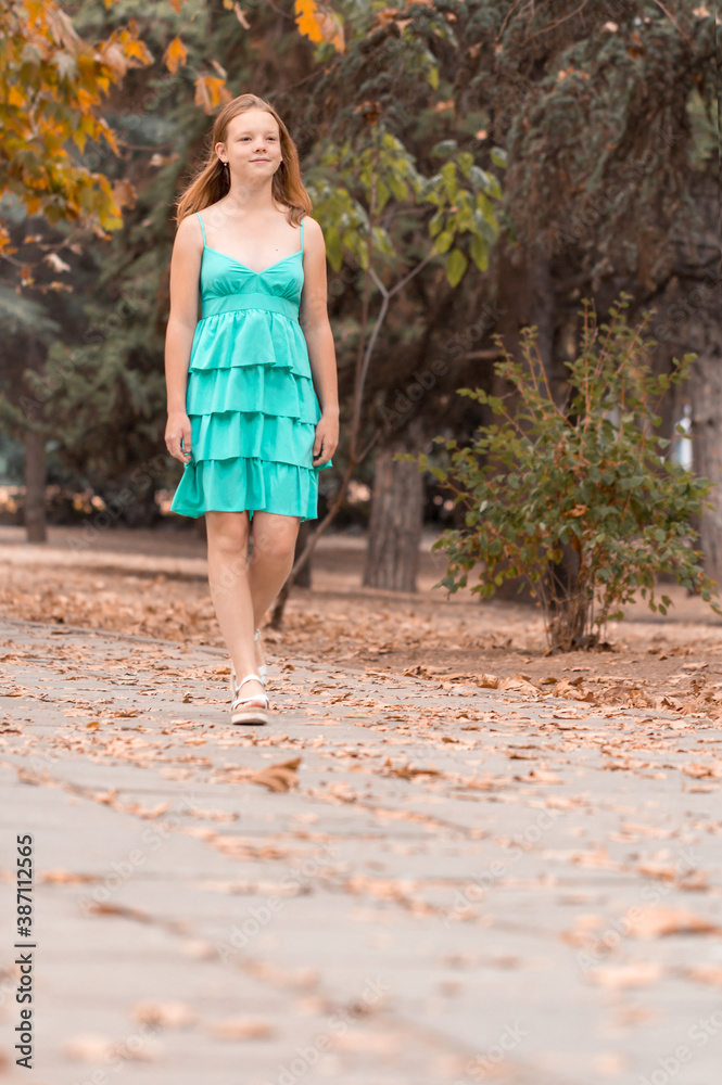 Cute young lady in blue short dress walks on fallen leaves of park Cute young lady in blue short dress walks on fallen leaves of park