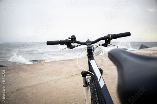 Close-up Of Bicycle Handlebar on the beach on rainy day with waves
