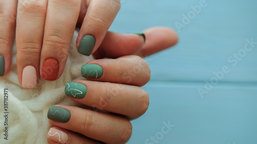 Women's hands with colorful pattern on the nails.