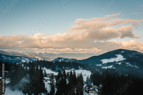 Amazing sky with clouds in the winter mountains. Houses in the snowy mountains in the morning.