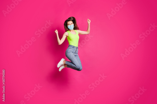 Fototapeta Naklejka Na Ścianę i Meble -  Full body photo of excited young girl celebrate jump up wearing blue face mask isolated over pink color background
