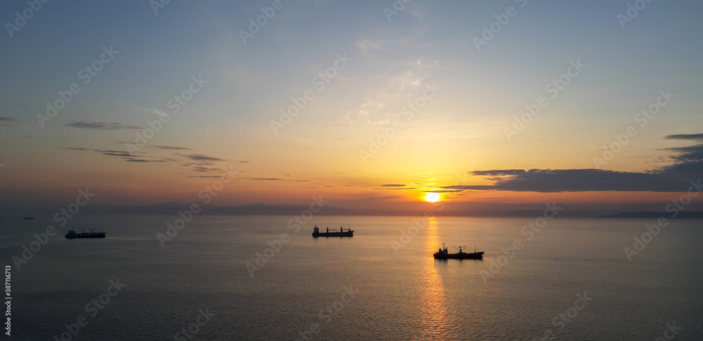 sunset in the sea with silhuettes of ships