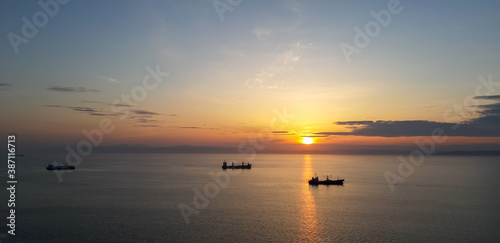 sunset in the sea with silhuettes of ships © Natalia Terenteva