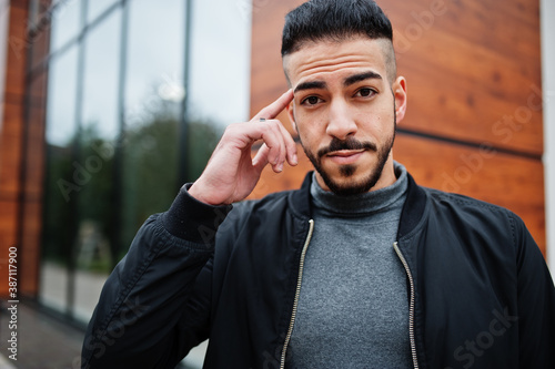 Just think about it. Portrait of stylish thinking man arab beard man wear grey turtleneck and black jaket. Arabian model guy. photo