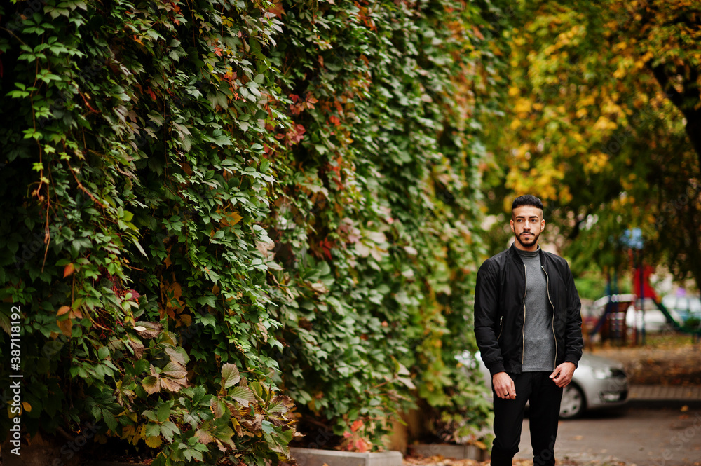 Portrait of stylish arab beard man wear grey turtleneck and black jaket. Arabian model guy on a background of autumn leaves. Portrait of stylish arab beard man wear grey turtleneck and black jaket. Arabian model guy on a background of autumn leaves.