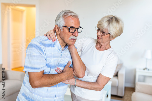 Senior man with neck pain and concerned elderly woman at home © Graphicroyalty
