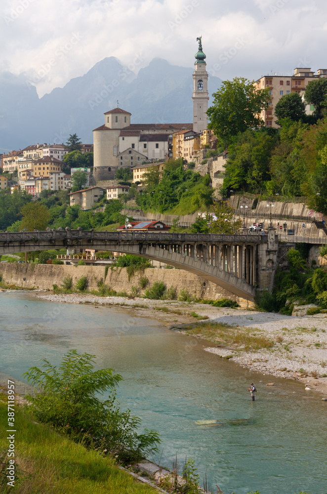 Skyline of Belluno, Italy, with the river Piave and the Vittoria bridge in the foreground