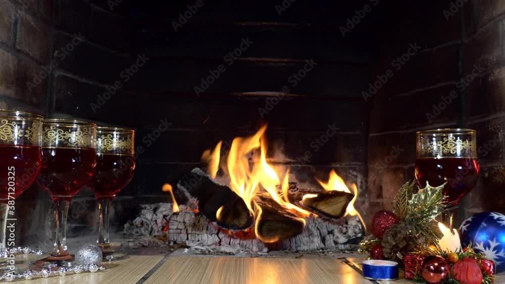 Christmas, New Year. A festive installation. Glasses with a drink and Christmas decorations on the background of the fireplace flame. Close up. Christmas, New Year. A festive installation. Glasses with a drink and Christmas decorations on the background of the fireplace flame. Close up.