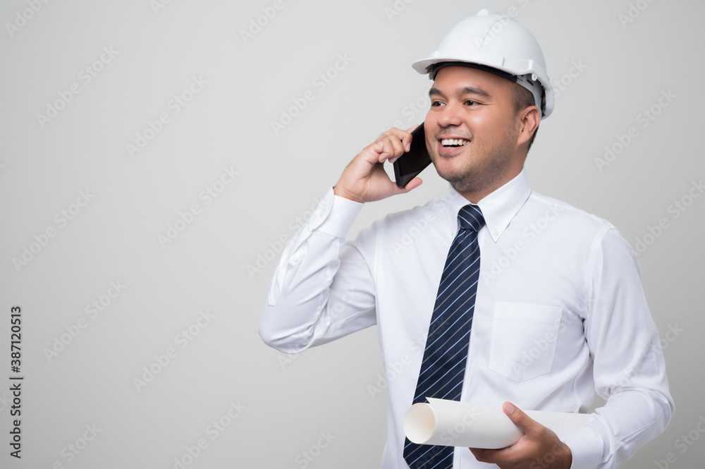 Asian engineer talking with customer on phone to home service. Worker wearing hard hat using smartphone standing on isolated white background.. Asian engineer talking with customer on phone to home service. Worker wearing hard hat using smartphone standing on isolated white background..