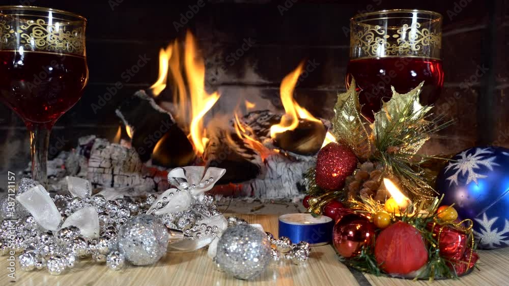 Christmas, New Year. A festive installation. Glasses with a drink and Christmas decorations on the background of the fireplace flame. Close up. Christmas, New Year. A festive installation. Glasses with a drink and Christmas decorations on the background of the fireplace flame. Close up.