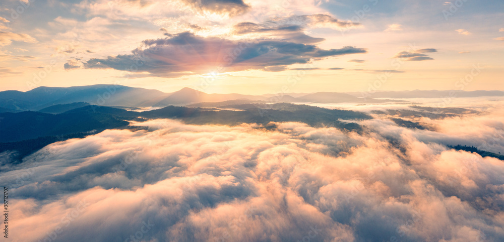 Flying above the clouds on drone. Panoramic morning view of Carpathian mountains with Homiak mountain on background. Fabulous sunrise on Ukraine, Europe. Beauty of nature concept background..