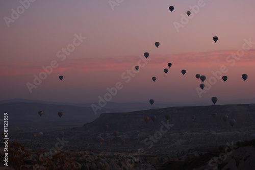 Hot air balloons flying over rocky landscape at sunset sky. Goreme, Cappadocia, Turkey.