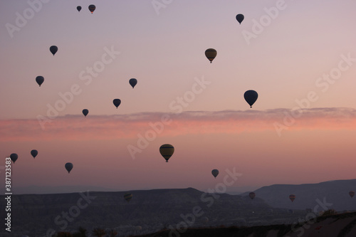 Red sunset sky with flying hot air balloons. Silhouettes of hot air balloons over sunset background. Concept of aerial adventure.