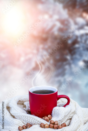 Red cup with coffee, tea on a snowy background, winter forest. A red cup against the background of a winter forest landscape on a soft, cozy scarf. Coffee, tea in the mountains.