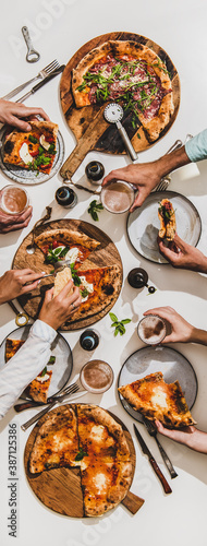 Pizza party for friends or family. Flat-lay of various pizzas, lager beer and people eating pizza over plain white table background, top view. Fast food, comfort food, Italian cuisine concept