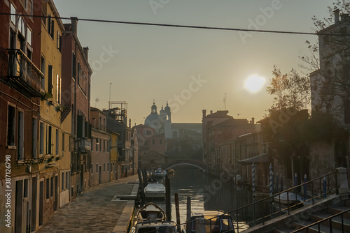 Venice, Italy - 24/01/18
Walm sunset and cozy atmopheric cityscape.
Gondola and boat at the port near the houses. photo