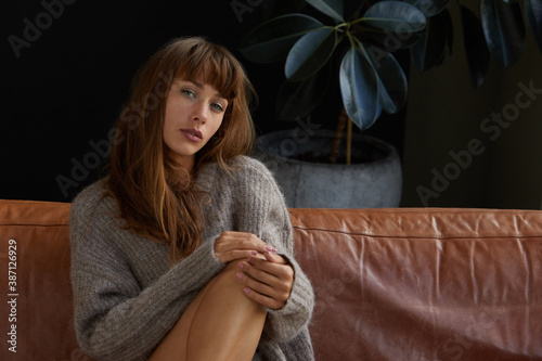 Young woman in a sweater sitting on a sofa photo