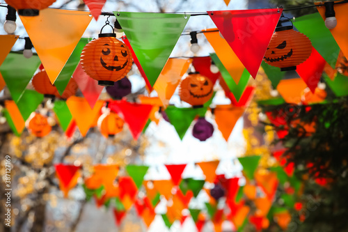 Colorful bunting paper cut  orange pumpkin lamps. Jack-o-lanterns hanging outdoors. Halloween street decoration  autumn holiday concept