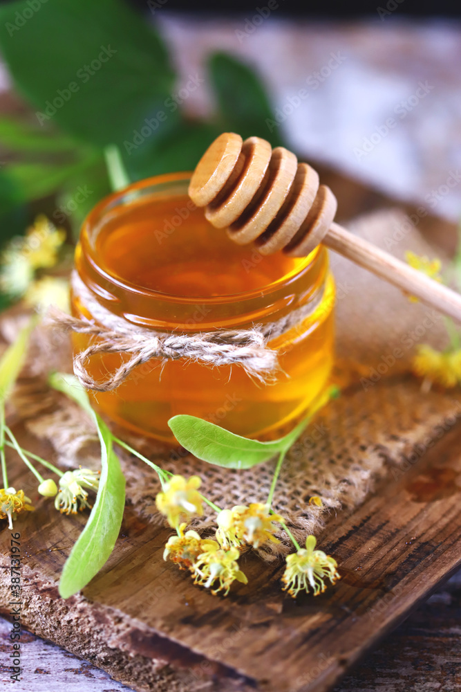 Selective focus. A jar of linden honey. Linden leaves and flowers. Linden honey concept. Selective focus. A jar of linden honey. Linden leaves and flowers. Linden honey concept.