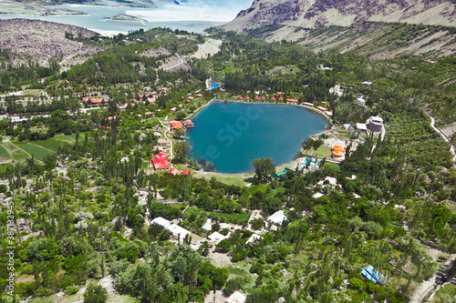 aerial view of a beautiful lake with blue water and lush green trees and red huts,around the lake, landscape of lake with mountains,  aerial view of shangrila resort in kachura lake skardu  photo