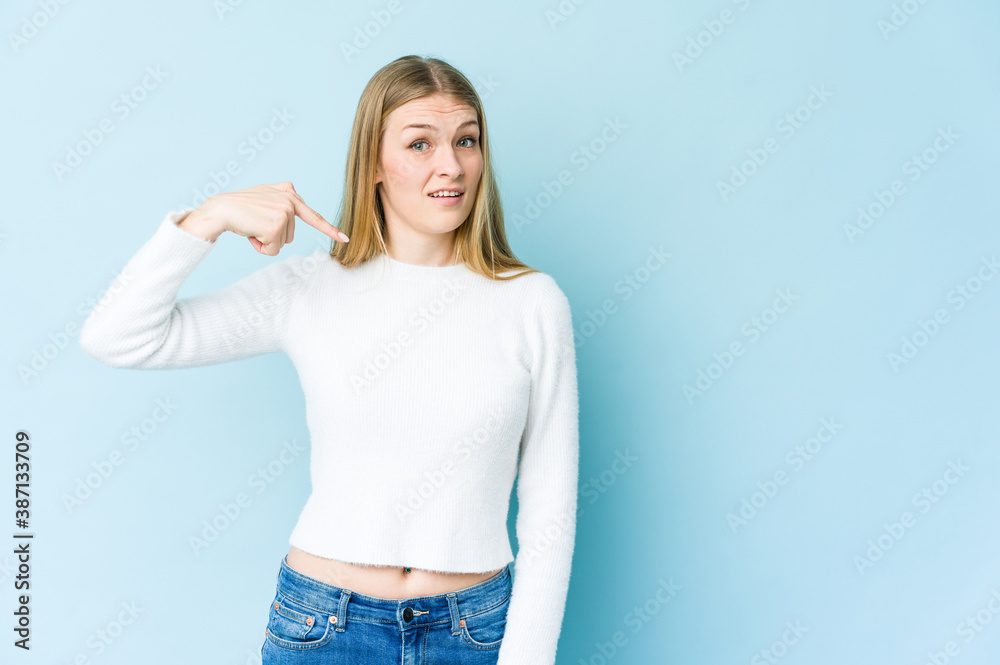 Young blonde woman isolated on blue background person pointing by hand to a shirt copy space, proud and confident Young blonde woman isolated on blue background person pointing by hand to a shirt copy space, proud and confident